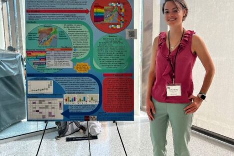 Woman standing in front of poster. Poster describes her research.